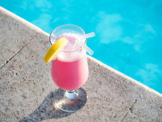 Glass with a beautiful milkshake on the background of the pool. View from above, close-up. Concept of leisure and travel