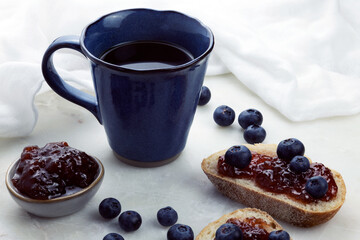 blue cup with blueberries and bread with jam