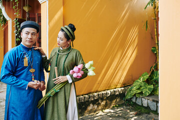 Young Vietnamese bride and groom in traditional ao dai dresses standing outdoors