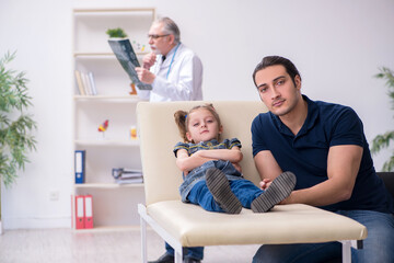 Young father and his daughter visiting old male doctor