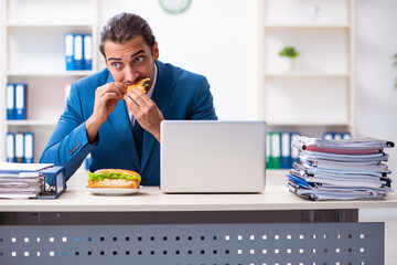 Young male employee having breakfast at workplace