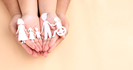 hands holding paper Cutout of different family members being together.