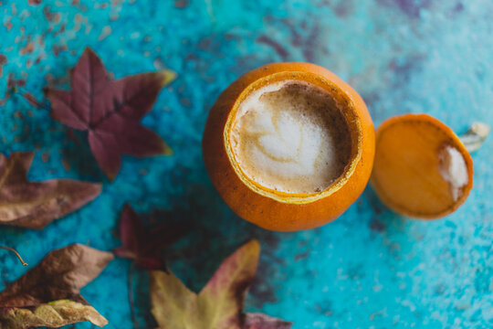 pumpkin spice latte with fall leaves on turquoise background