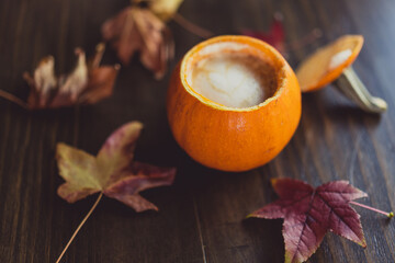 pumpkin spice latte in pumpkin cup with fall leaves