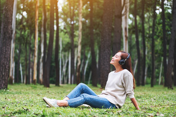 A beautiful young asian woman enjoy listening to music with headphone with feeling happy and relaxed in the park
