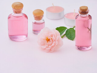 Obraz na płótnie Canvas Aromatherapy oil bottles and pink rose