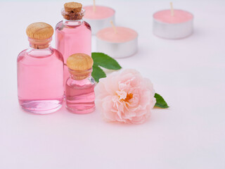 Obraz na płótnie Canvas Aromatherapy oil bottles and pink rose