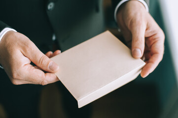 Close up of adult serious man's hands holding a white envelope without inscriptions.