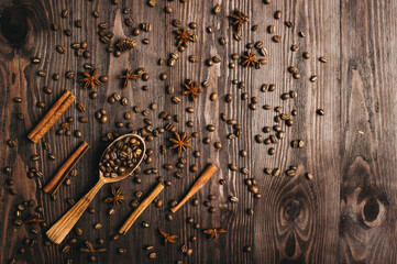Top view of wooden vintage spoon, coffee beans, cinnamon and star anise on wooden background.