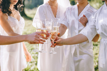 Morning of the bride. Close up of glasses of champagne in the hands of bridesmaids and brides.