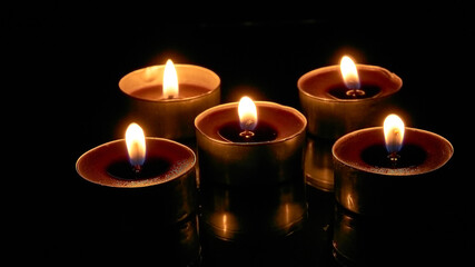 Burning candles on a black background, selective focus, romantic setting, romantic atmosphere, shot with shallow depth of field.
