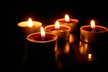 Burning candles on a black background, selective focus, romantic setting, romantic atmosphere, shot with shallow depth of field.