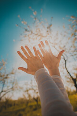 Human hands covering the bright sunlight that passes through the fingers.