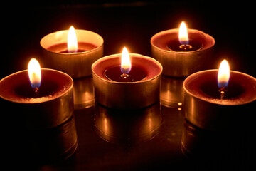 Burning candles on a black background, selective focus, romantic setting, romantic atmosphere, shot with shallow depth of field.