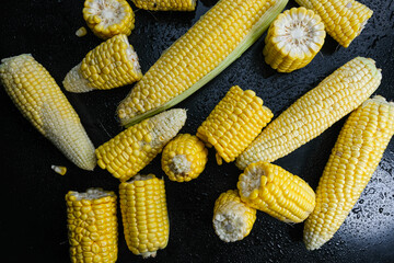 Fresh raw sweet corn cobs on black background