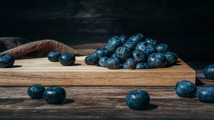 Blueberries on a wooden tray in a dark rustic style