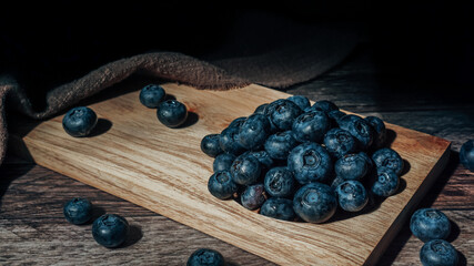 Blueberries on a wooden tray in a dark rustic style