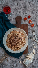 Baked Fusilli topped with minced meat and torched cheese on a grey concrete background