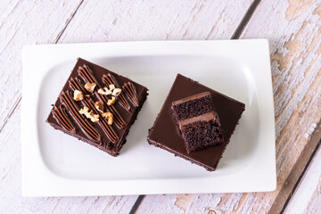 chocolate cakes pastries brownies on white ceramic plate with nuts topping  on a white wooden rustic desk table