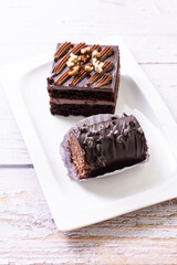 chocolate cakes pastries brownies on white ceramic plate with nuts topping  on a white wooden rustic desk table