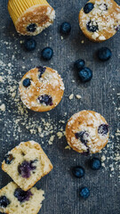 Scattered Blueberry muffin topped with crumble on a dark textured background