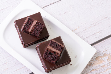 chocolate cakes pastries brownies on white ceramic plate with nuts topping  on a white wooden...