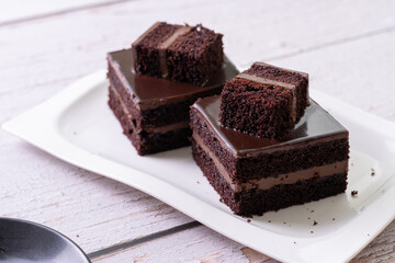 chocolate cakes pastries brownies on white ceramic plate with nuts topping  on a white wooden rustic desk table