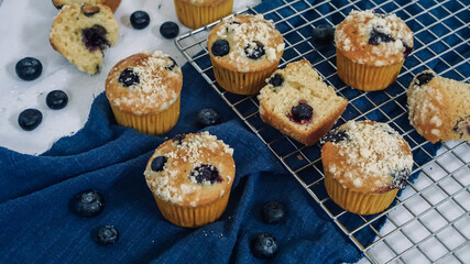 Crumbled Blueberry muffin on a blue cloth and white marble background