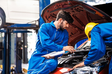 Fototapeta na wymiar Mechanic checking the opened hood car with his assistant. Auto car repair service center. Professional service.