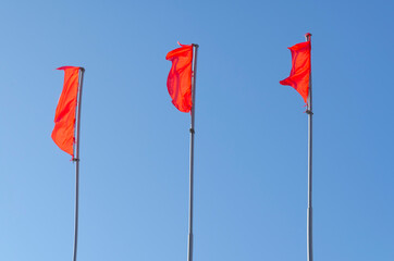 Three red flags on a blue sky background.