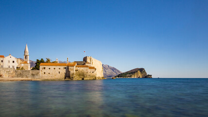 Fototapeta na wymiar Strand mit himmel und Stadtmauer mit Burg und hafen von Budva in Montenegro