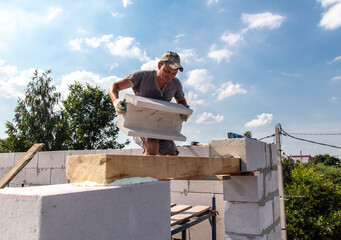 Worker builder lays foam brick in the wall