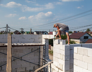 A worker builds the walls of a house from aerated concrete bricks.