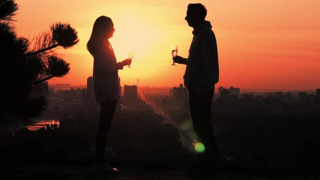 woman and man holding wine glasses on the background top view on urban cityscape at sunrise