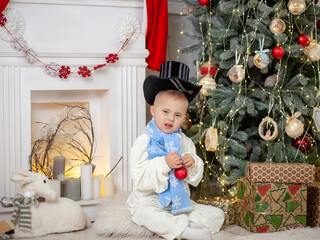 A boy with Down syndrome decorates a Christmas tree with balls, a child with a disability in a...
