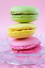 Vertical pile of three colorful french cookies made of almond flour called macarons on glass plate