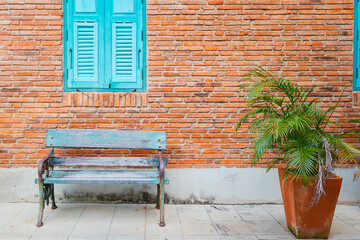 Empty bench and decorative tree on brick wall background with window.