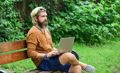 Obraz premium Homeschooling concept. online distant education. hipster inspired work in park. agile business. mature student working on computer. go shopping on cyber monday. bearded man sit on bench with laptop