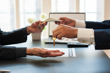 The concept of real estate trading and housing. Businessmen pay and receive house keys from real...