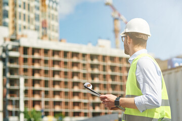 Young civil engineer wearing helmet inspecting building site, engineering and architecture concept