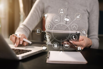 Fashion designer woman talking smart phone and using laptop with digital tablet computer in modern studio in morning light.