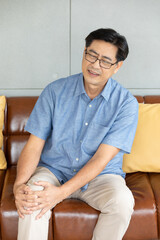 senior asian man suffering from knee ache at home