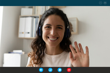 Close up screen view portrait of smiling Caucasian woman in headphones talk on video call wave...