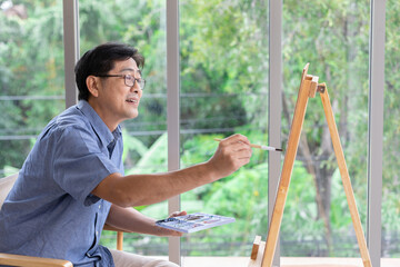 senior asian man painting at home