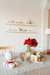 Bright modern home kitchen interior concept. Paper gift box, red flowers, candles. Cozy comfortable interior design decorated for Christmas / New Year celebration.