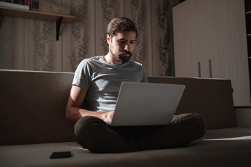 Remote Job. Man Working On Laptop Sitting On Sofa At Home.