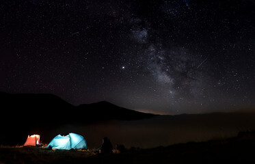 Iluminated tents in the mountains. Starry sky with the milky way in Pajares, Spain.