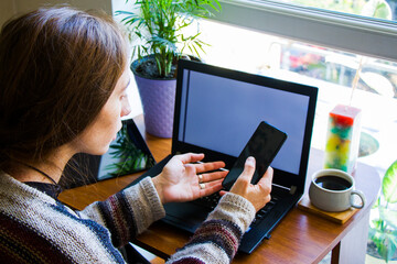 Woman working with notebook in workplace, digital tablet, mobile phone, coffee and plants