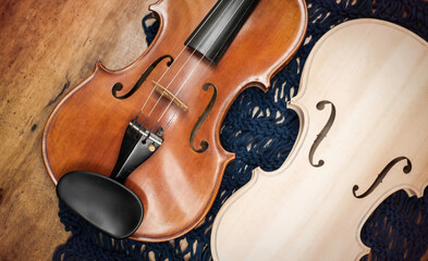 Front side of Raw violin and completed violin put on wooden timber board.