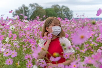 Obraz na płótnie Canvas コスモス畑にいるマスクをした若い女性